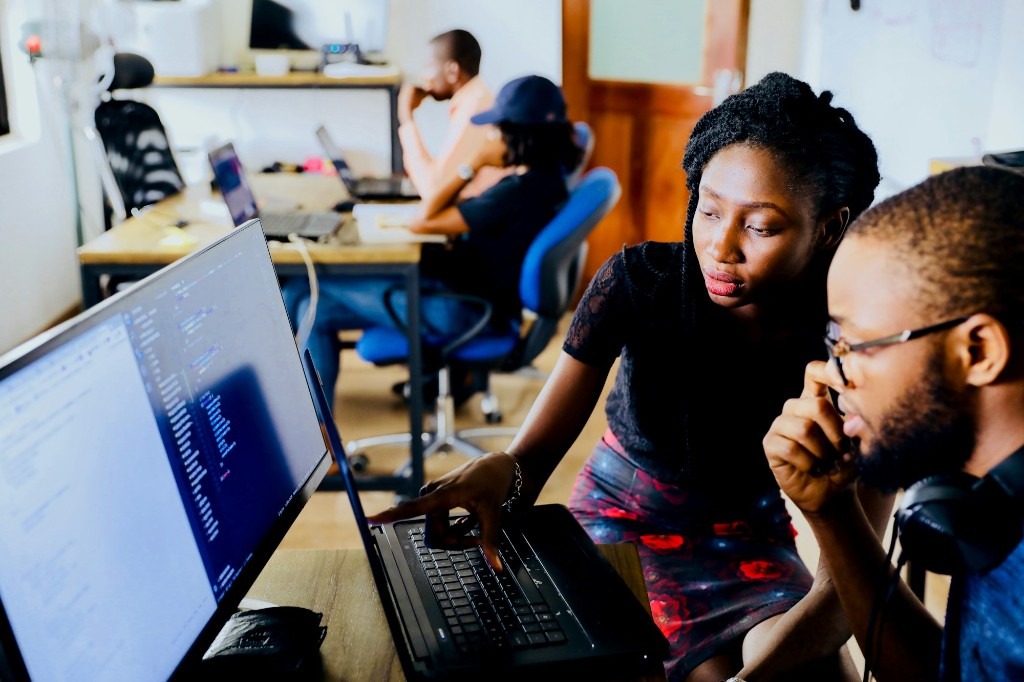 Developers collaborating at a computer with code on screen in a modern office